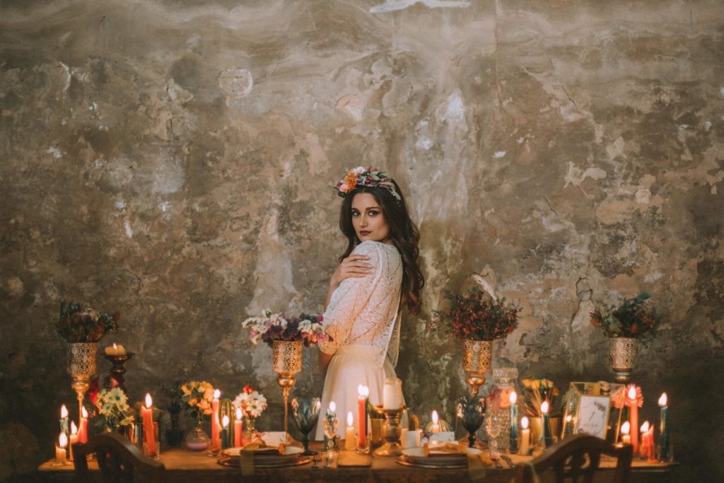 Bride in an abandoned fabric behind a table full of candles and flowers